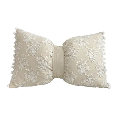 Beige bow-shaped cushion cover with white lace floral embroidery and pom-pom trim decorbites boho white style