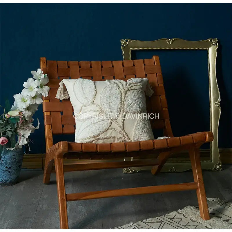 Cream-colored geometry tufted cushion cover with embroidered leaf design and tassel accents on woven wooden chair decorbites boho leaf