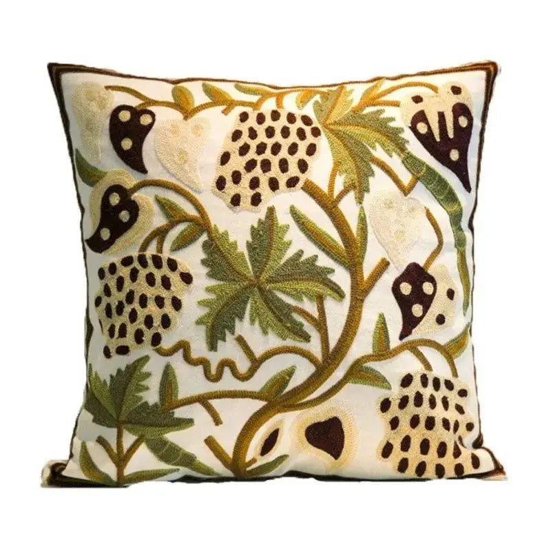 Cream-colored square pillow cover with intricate boho farmhouse floral embroidery in olive, mustard, and dark brown threads