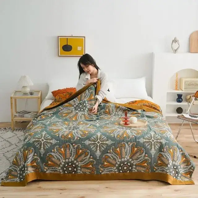 A cozy teal and gold boho floral cotton gauze leisure blanket quilt draped over a bed for decorbites cotton gauze decor