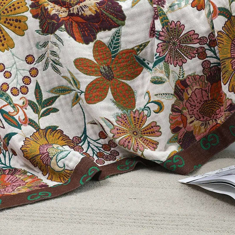 A gucci embroidered boho cotton bedspread with vibrant orange pink and yellow floral designs on a cream background