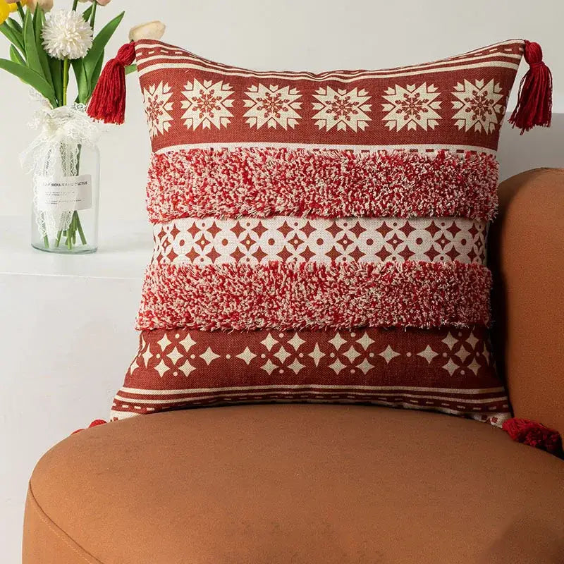 Red and cream patterned throw pillow with textured fringed stripes and tassels.