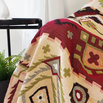 A cozy throw blanket with a vibrant red beige green and black geometric pattern for boho geo ethnic decorbites style