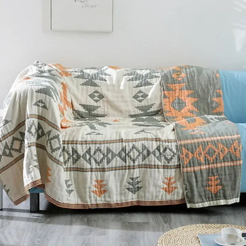 A cozy decorbites boho cotton throw blanket with a geometric tribal pattern in cream gray and orange for sofa decor
