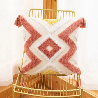 Cream-colored cushion cover with coral and yellow tufted embroidery and fluffy tassels for boho living room decor