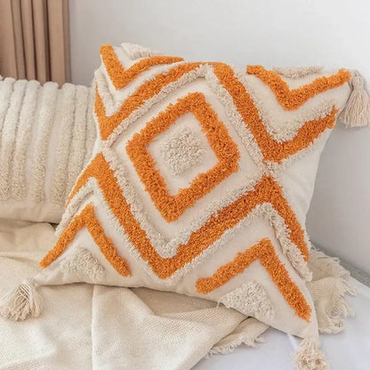 Cream-colored pillow cover with orange and cream decorbites geometric tufted patterns and tassels for living room decor