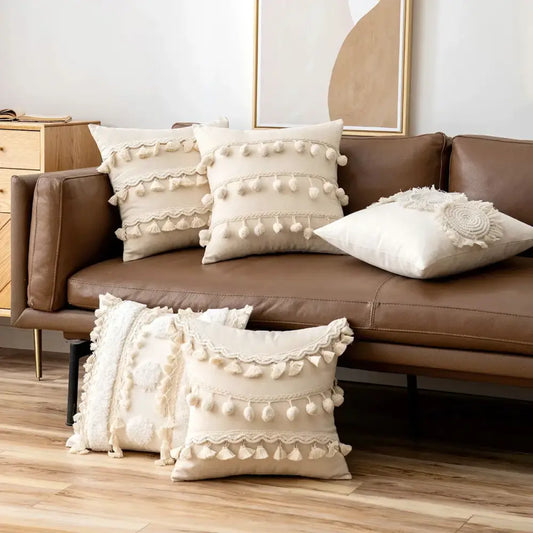 Cream-colored boho ivory cushion cover with pompoms and lace trim on brown leather sofa for living room decorbites ivory cushion