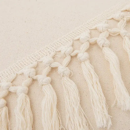 Cream-colored boho macrame woven cushion cover with cotton knotted tassels and fringe for bedroom decor by decorbites