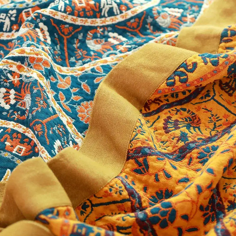 Cozy quilted throw blanket with vibrant blue and mustard-yellow cotton boho manta featuring embroidered animals and foliage