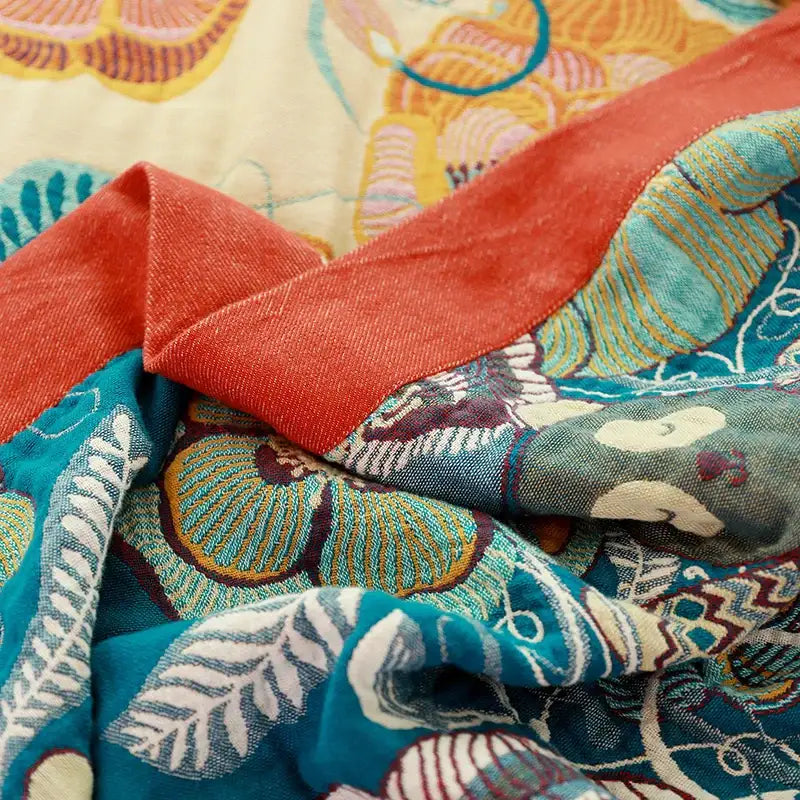 A vibrant teal and coral decorbites cotton boho throw blanket with white gold and brown floral embroidery for bedroom decor