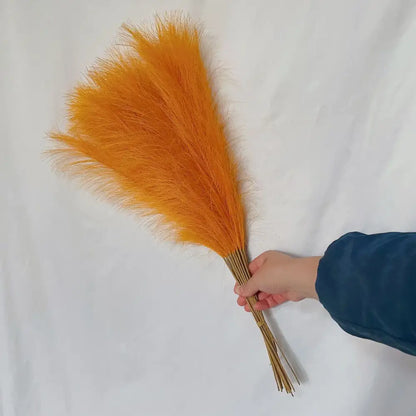 A vibrant orange feather duster with natural bamboo grip paired with boho white and beige fluffy pampas grass decorbites fluffy pampas