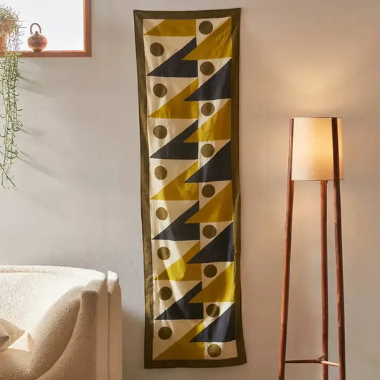 A long narrow silk scarf with bold yellow triangles and black circles celestial geometry tapestry design