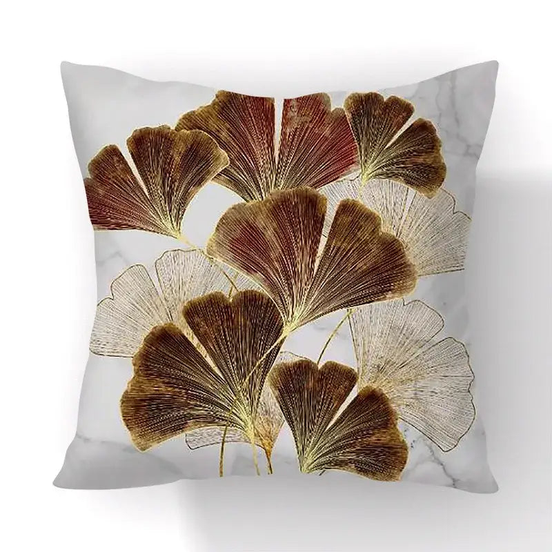Square cushion cover with golden and brown big leaves on white marble background for living room decor