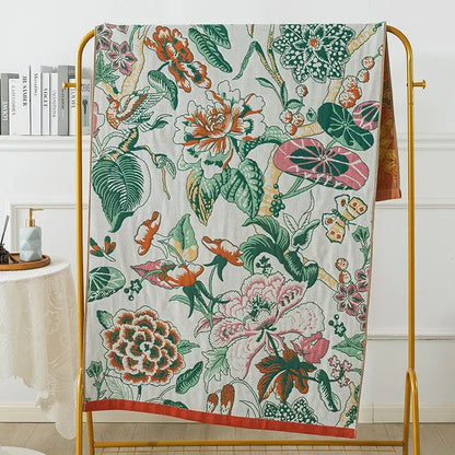 Botanical blue and orange cotton gauze bath towel with vibrant orange pink and green floral pattern on cream background