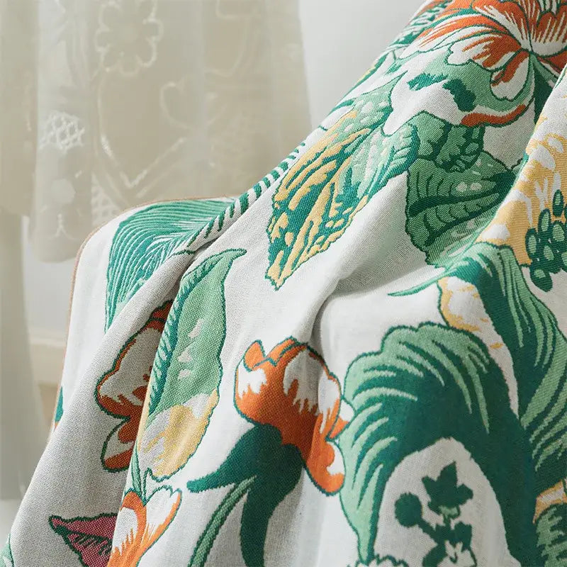 A soft white decorbites cotton gauze bath towel featuring vibrant green leaves and orange blossoms botanical design