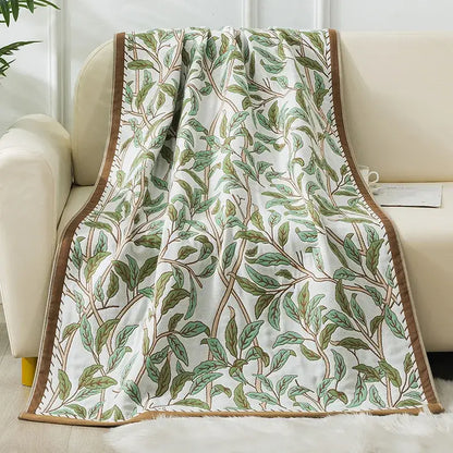 A soft white decorbites cotton gauze bath towel with embroidered green and brown leaves and tan trim for bathroom decor