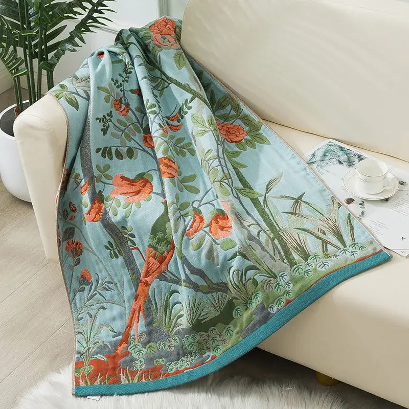 A soft light blue decorbites cotton gauze bath towel with vibrant orange flowers and green foliage botanical print
