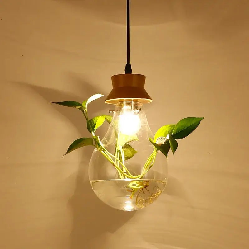 Botanical glass bottle pendant light with clear glass bulb, warm wood shade, filament, and green vine decorbites botanical glass