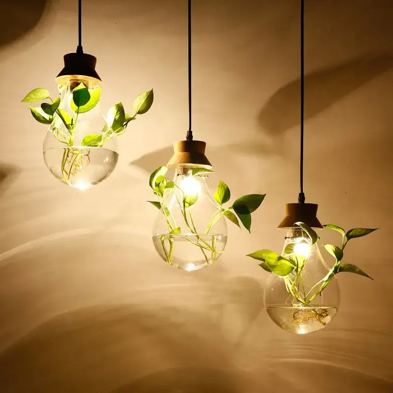 Three clear botanical glass bottle pendant lights with water and green plants hanging with wood accents for kitchen decorbites botanical glass decor