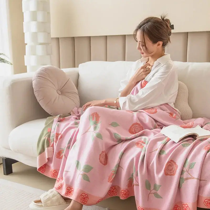 Botanical white and gray bamboo four layer summer quilt with pink rose patterned blanket draped on woman on couch