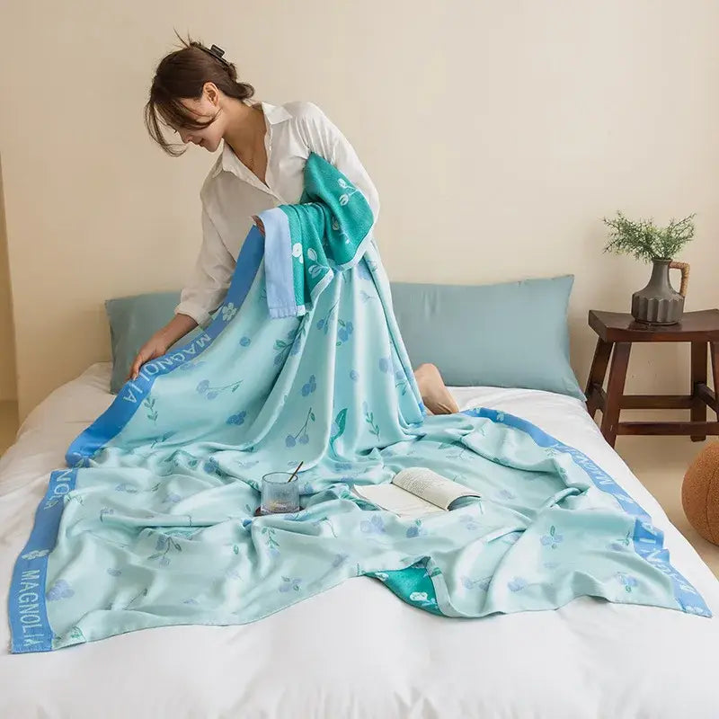 A soft light blue decorbites bamboo four layer summer quilt with floral pattern and teal magnolia border