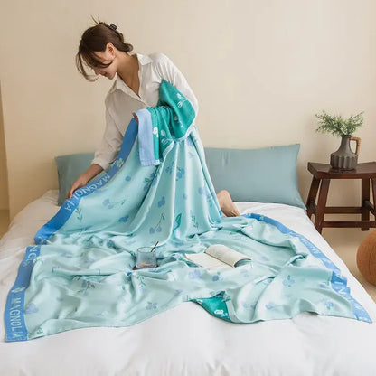 A soft light blue decorbites bamboo four layer summer quilt with floral pattern and teal magnolia border