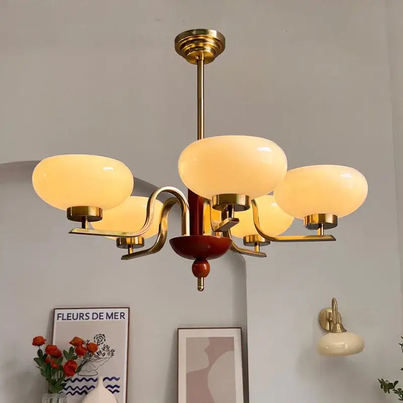 Brass and cream glass pendant chandelier featuring five warm opalescent shades and a central wooden accent for dining room decorbites cream glass
