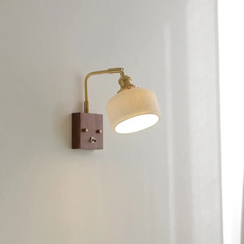 A warm-toned brass and walnut ceramic led wall light with ribbed off-white fabric shade for bedroom decorbites ceramic led wall