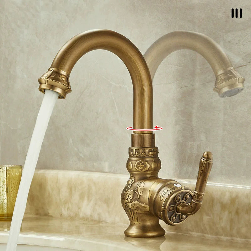 Antique brass bathroom sink faucet with ornate floral and scrollwork detailing on base handle and spout