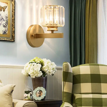 Gold-toned brass wall sconce with faceted decorbites crystal glass shade for elegant bedroom lighting