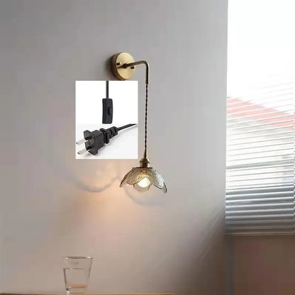 Antique brass wall lamp with a gray glass led shade shaped like an open flower for bathroom lighting