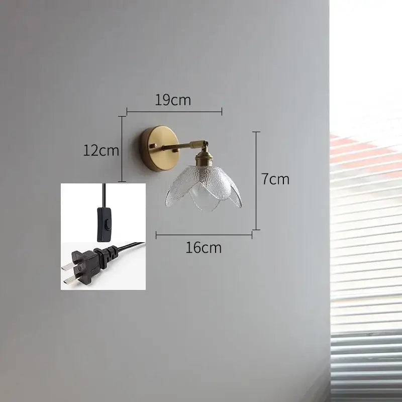 A delicate brass wall lamp with gray textured glass led shade shaped like a flower for bathroom use