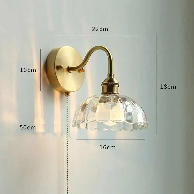Brass-finished led wall sconce with a clear faceted glass copper led shade shaped like an open flower and pull chain