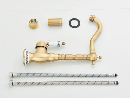 Antique brass finished deck mounted kitchen faucet with rotating neck and white ceramic handle featuring black floral engraving