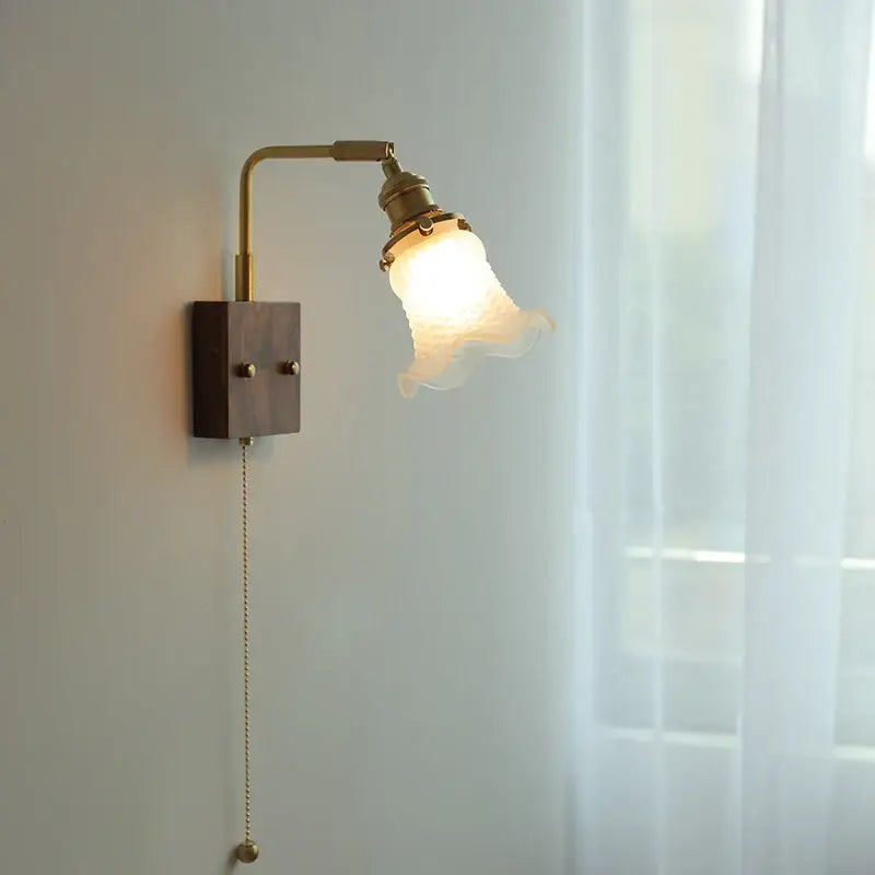 Brass walnut wood wall sconce with brass finish dark wood base and off-white petal-shaped glass shade for decorbites