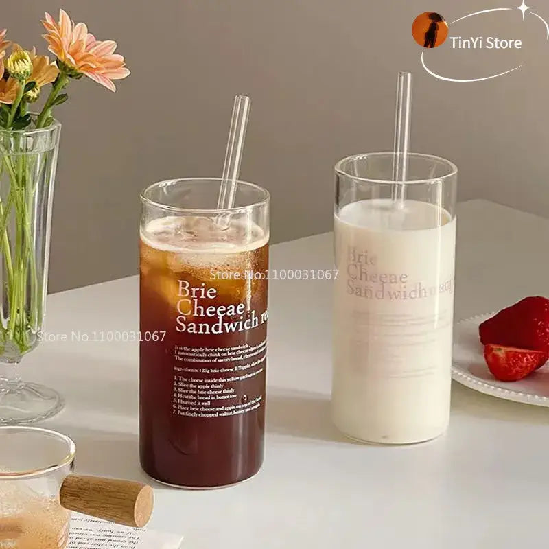 Tall clear glass coffee mug with brie cheese sandwich print filled with iced coffee and a straw for kitchen use