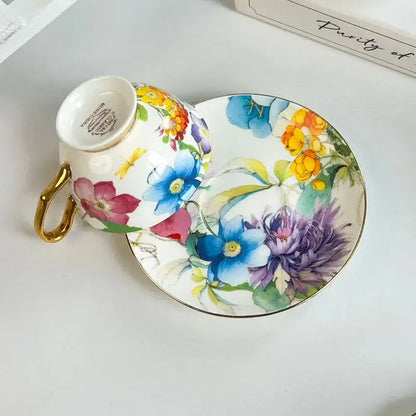 A delicate porcelain teacup and saucer with a brilliant flowers pattern in vibrant colors and gold accents for dining use