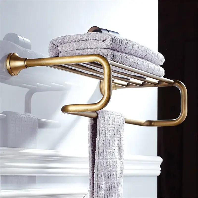 Brass-finished curved multi-tier towel rack holding gray towels as part of decorbites bronze bathroom accessories set