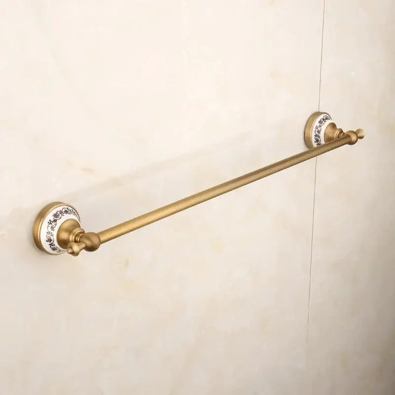 Antique brass towel rack with white ceramic end caps and black floral patterns in decorbites bronze bathroom hardware set