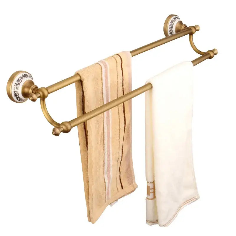 Brass double towel rack with ornate ceramic end caps and two towels in decorbites bronze bathroom hardware set
