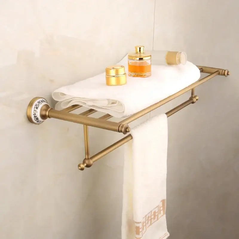 Bronze bathroom hardware set featuring a brass towel rack with decorative ceramic mounts and dual bars holding a white towel