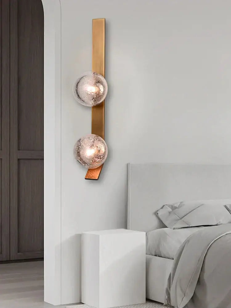 Bronze bubble glass wall sconce lamps featuring two frosted glass spheres on a vertical brass bar for bedroom use
