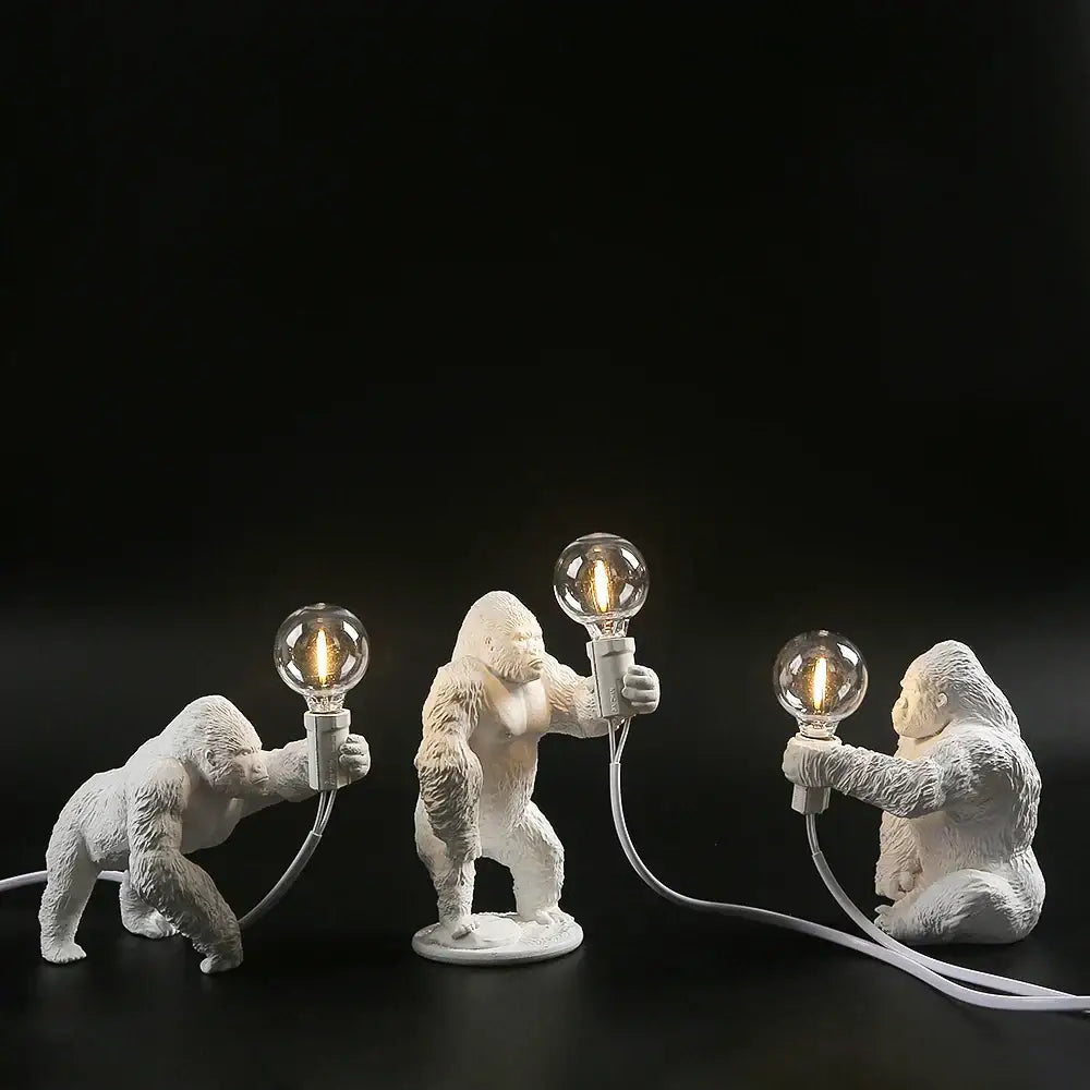 Three white king kong gorilla table lamps holding glowing bulbs connected by cords by decorbites for bedroom decor