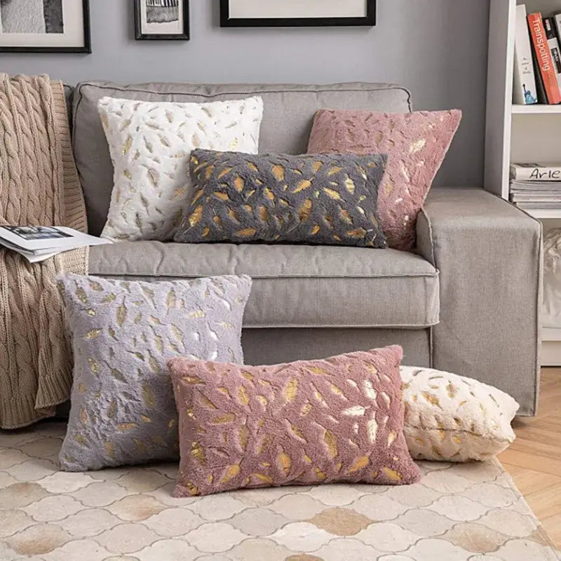 A plush dusty rose throw pillow with bronzed feather style gold foil leaves for elegant living room decor