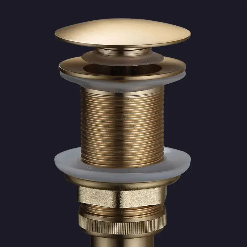 Brass-finished bathroom sink drain with rounded domed top and threaded body in brushed gold and white ceramic drain assembly kit