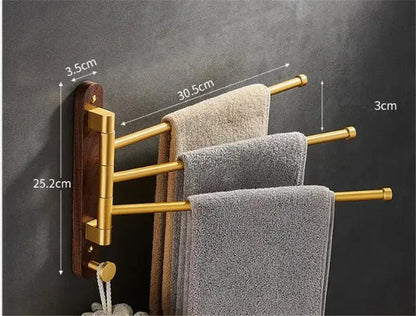Brushed gold swivel towel hanger with dark wood base holding three beige and gray towels for bathroom use