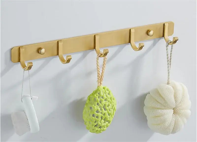 Brushed gold metal wall-mounted robe hooks with five hooks holding bath accessories by decorbites brushed gold
