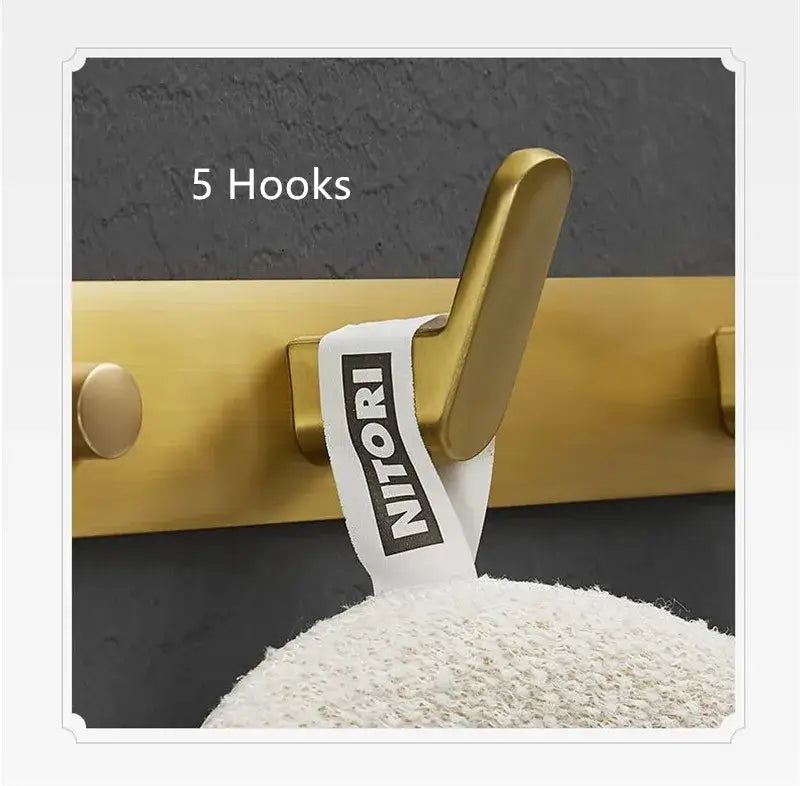 Brushed gold robe hook with white fabric tag bearing the nitori brand for bathroom and kitchen decorbites brushed gold