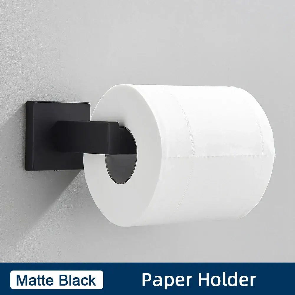 Matte black wall-mounted paper holder holding white toilet paper in a brushed gold stainless steel bathroom accessories set