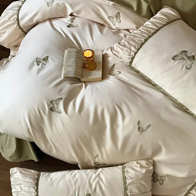 Cream-colored satin bedding set with decorbites butterfly embroidery and ruffled edges for elegant bedroom decor